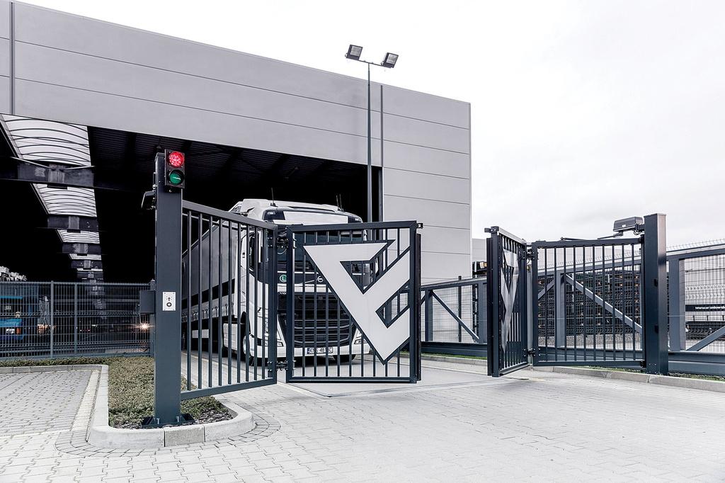En robust, nymonterad skjutgrind i stål skyddar infarten till en industrifastighet.
